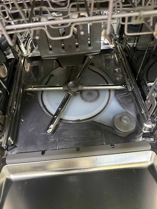 Dishwasher tub floor with the lower spray arm and sump area from above