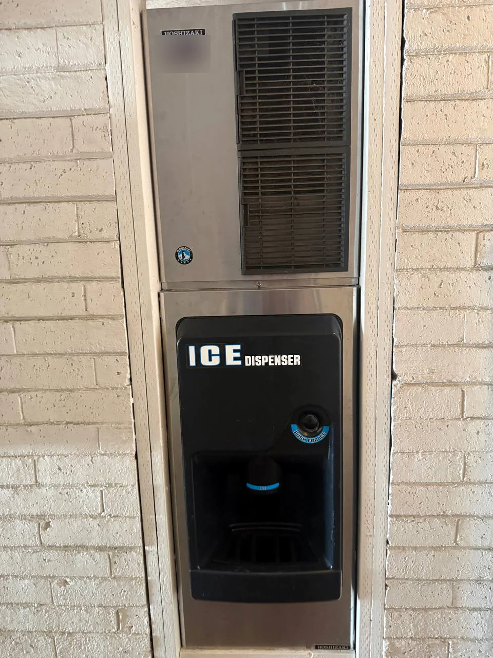 Hoshizaki ice machine with dispenser mounted on a painted brick wall
