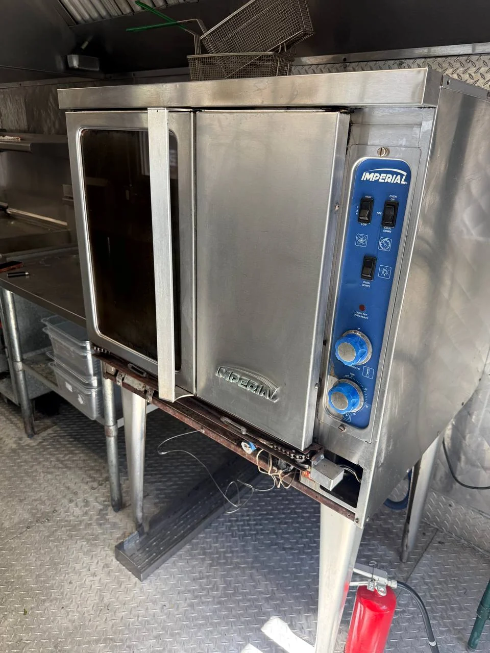 Imperial commercial convection oven with the door ajar and lower panel open showing loose wiring