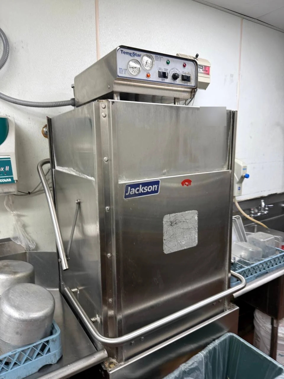 Jackson stainless commercial dishwasher with a control box on top beside dish racks